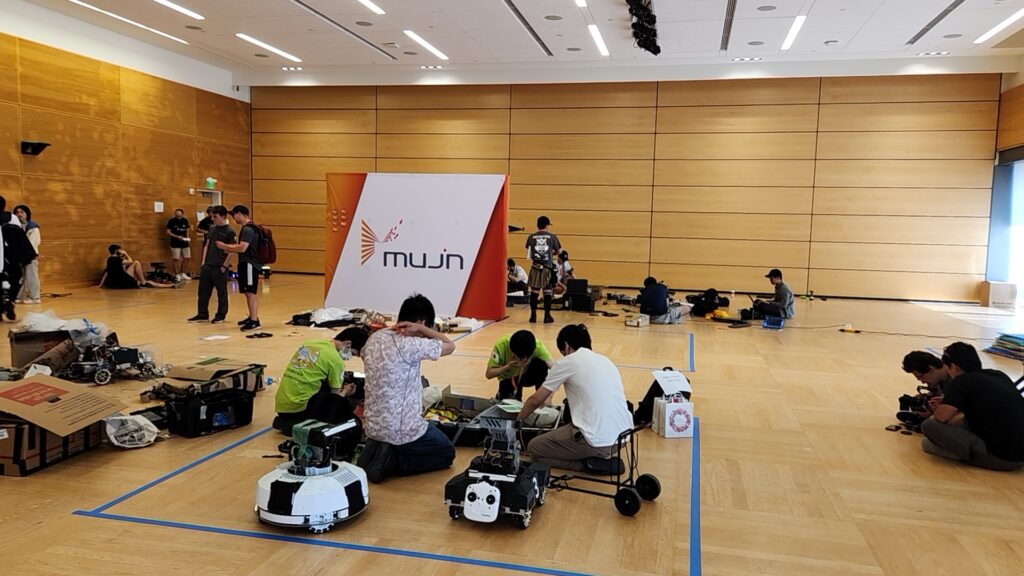 Teams working with RoboMaster robots in the pit area.