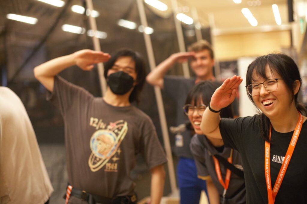 Team members saluting during the RoboMaster competition.